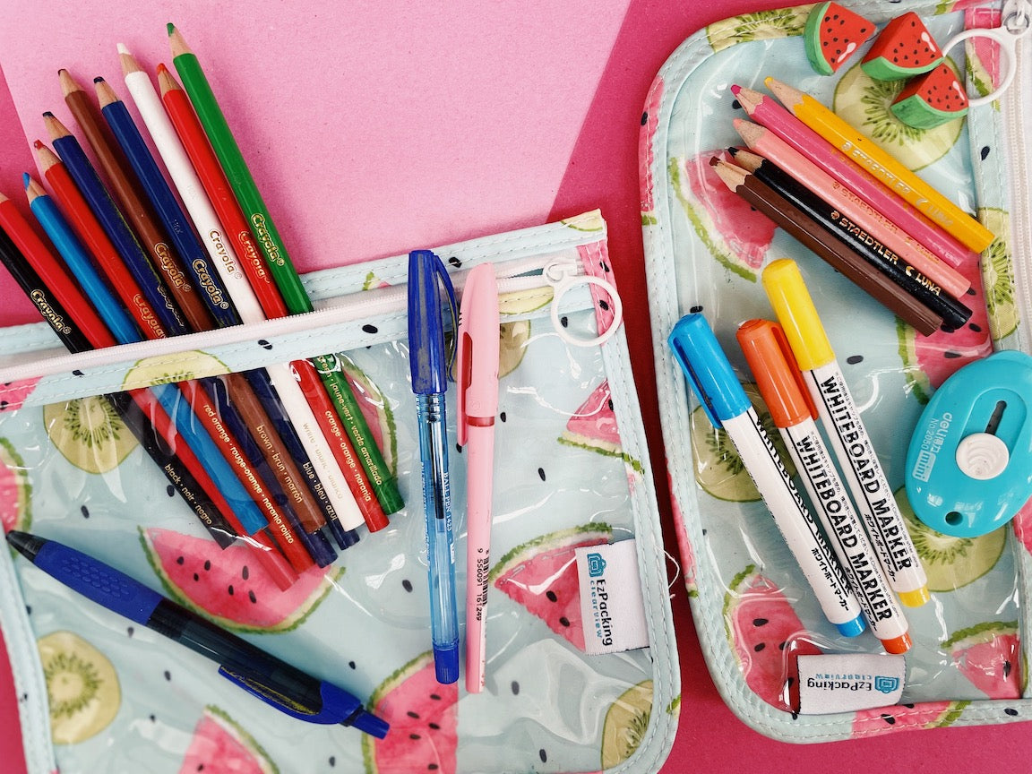 Clear zipper pouches with school supplies like color pencils, pens, and erasers